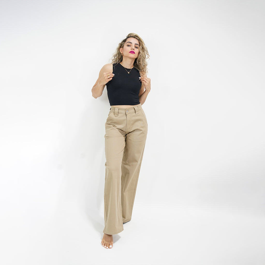 Woman wearing a black top and beige pants on a white background