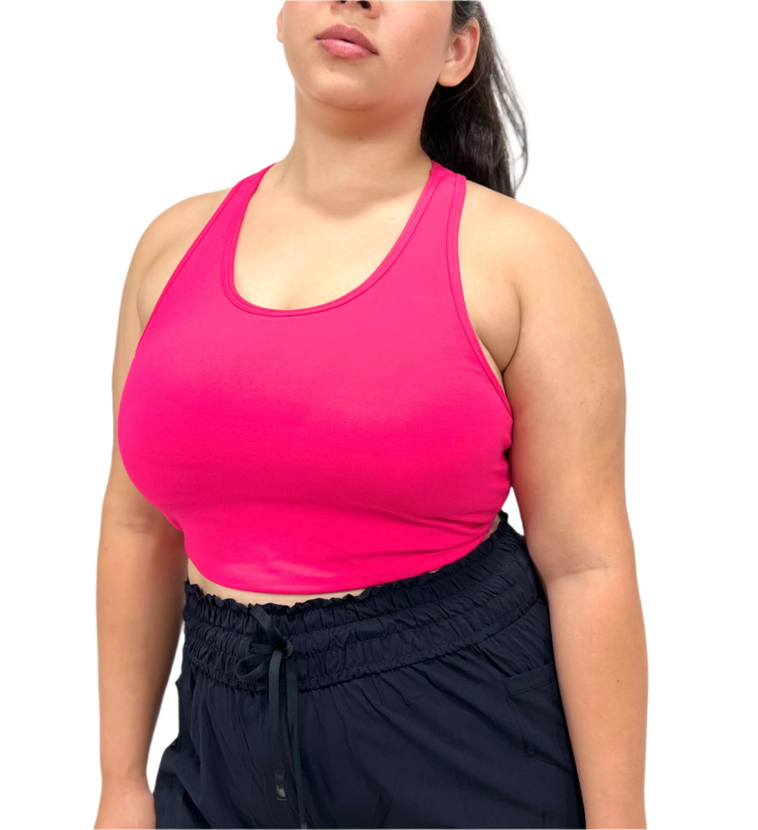 Person wearing a bright pink sports bra and navy pants on a white background