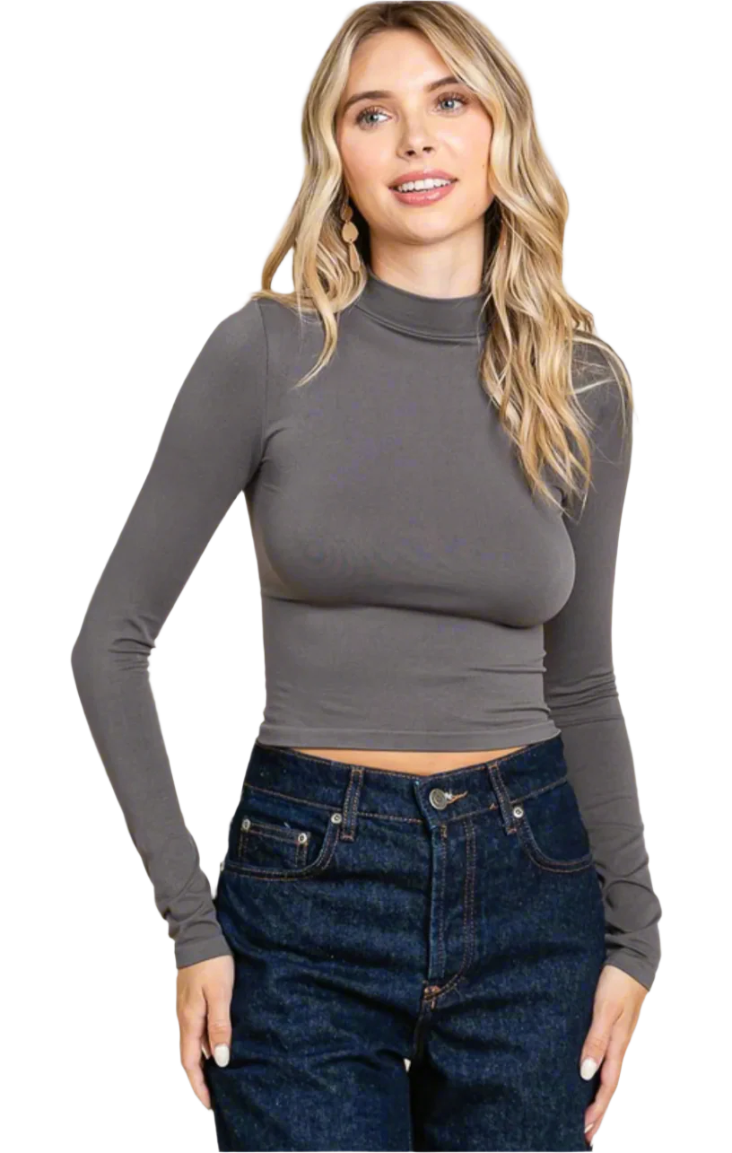Woman wearing a gray long-sleeve top and blue jeans on a white background