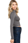 Woman wearing a gray long-sleeve top and blue jeans on a white background