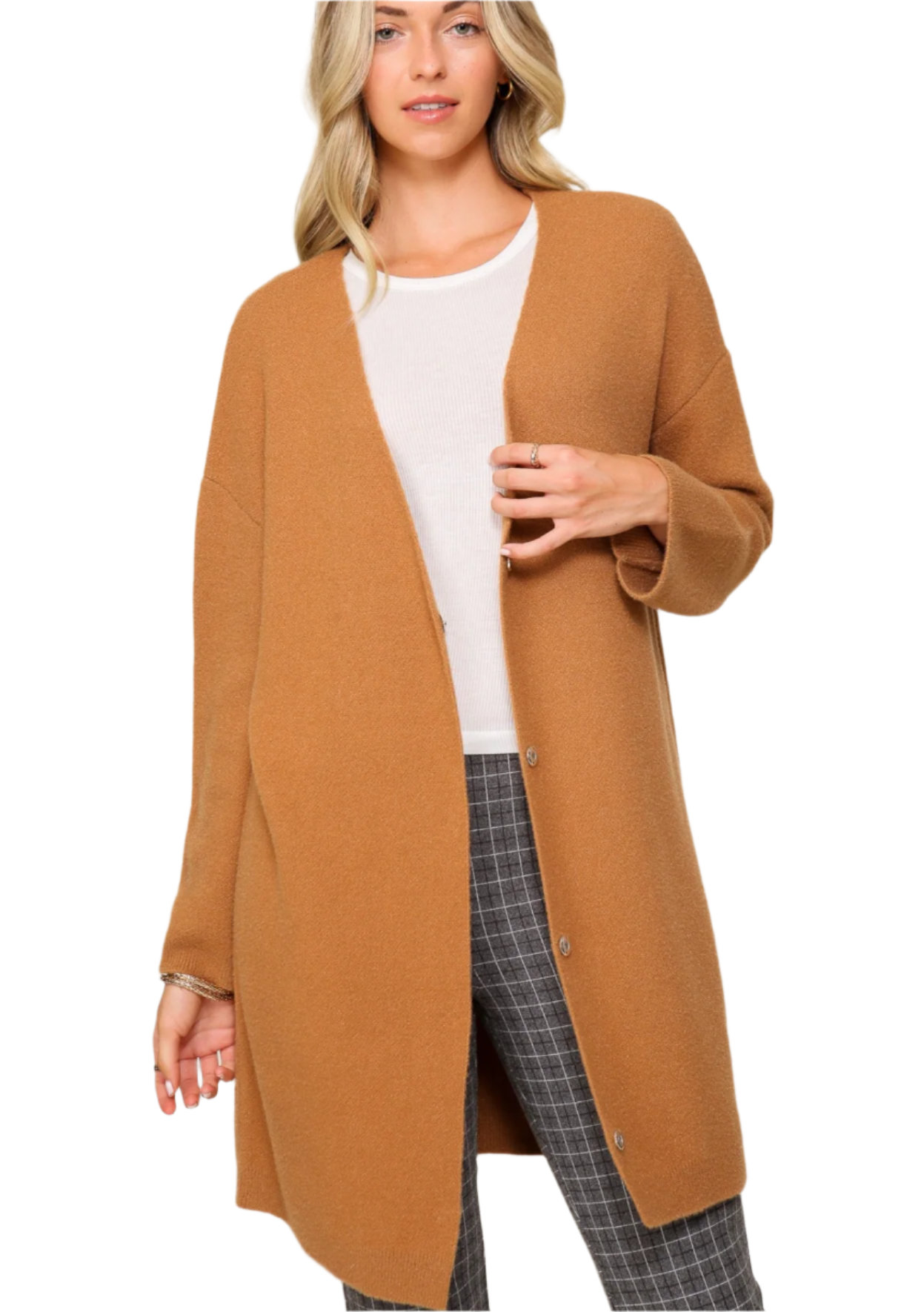 A woman wearing a brown oversized button-down cardigan with long sleeves, paired with a white top and checkered pants.