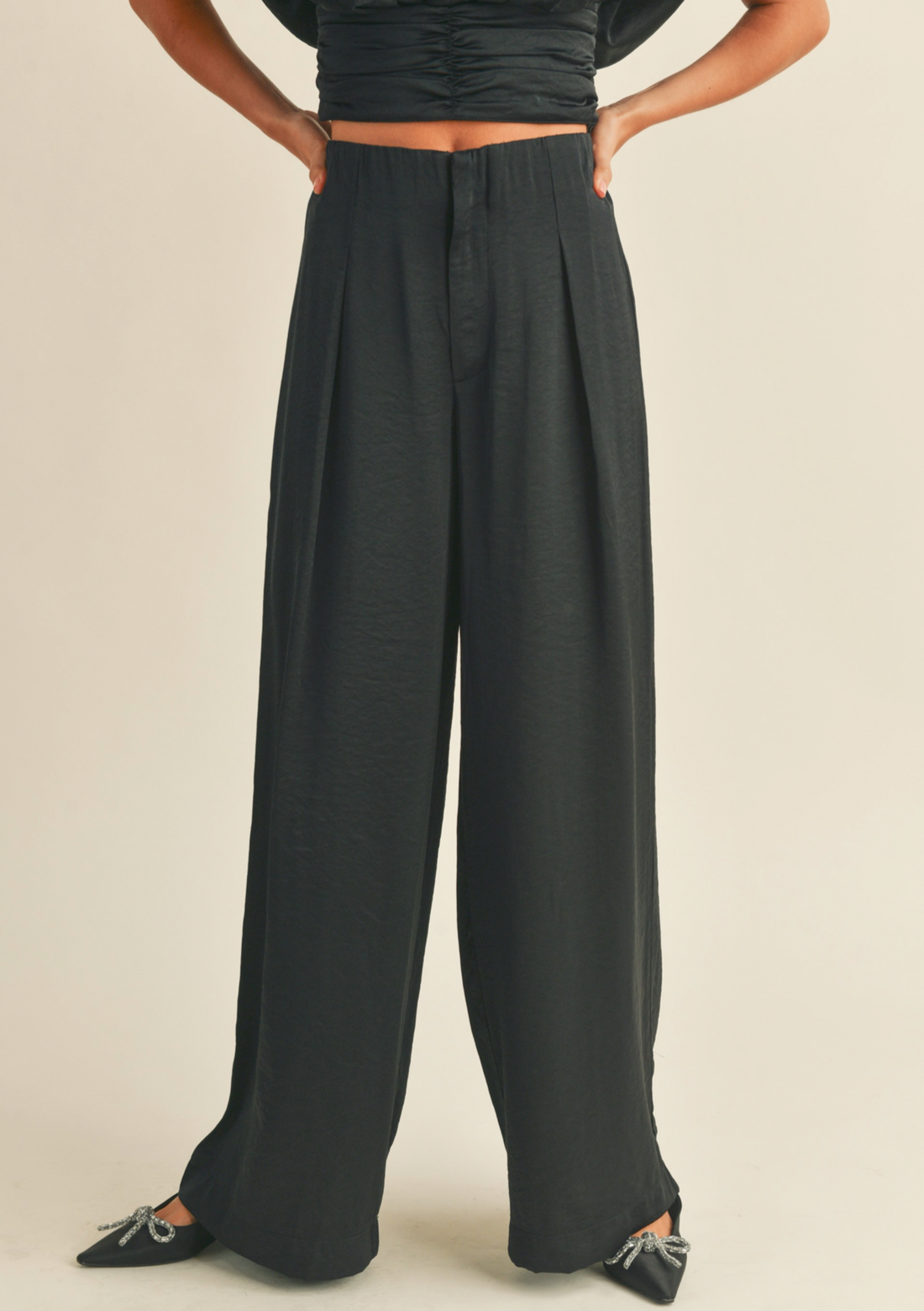 Black wide-leg pants worn by a person on a white background