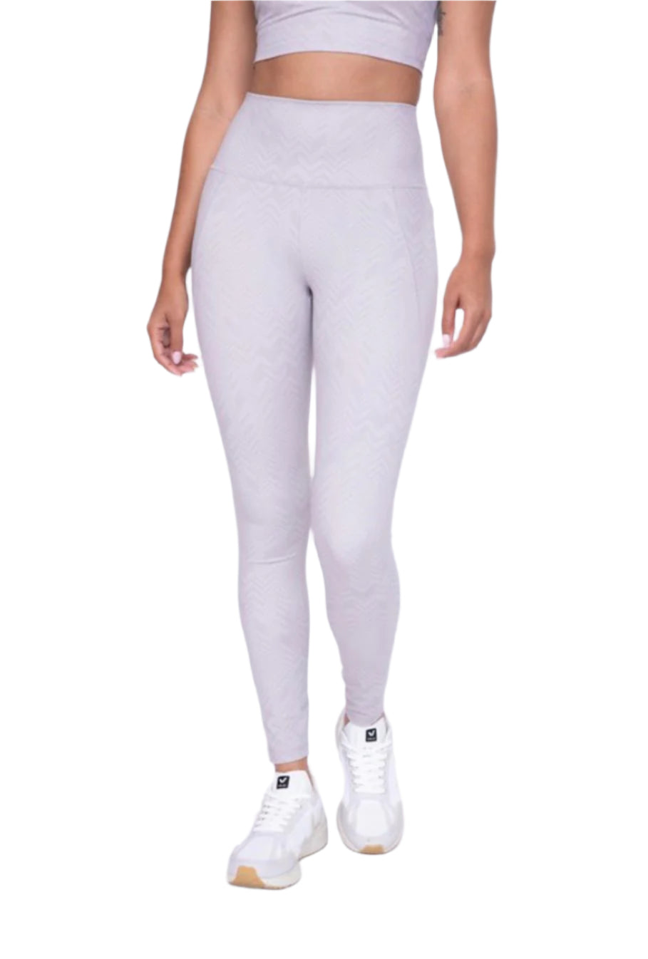 Person wearing light gray leggings and white sneakers on a white background