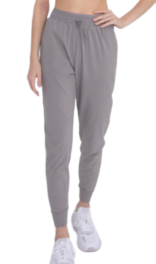 A person wearing gray tapered joggers with adjustable drawstrings at the waist.