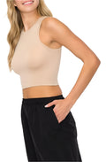 A female model wearing a round neck sleeveless top in beige, paired with black trousers.