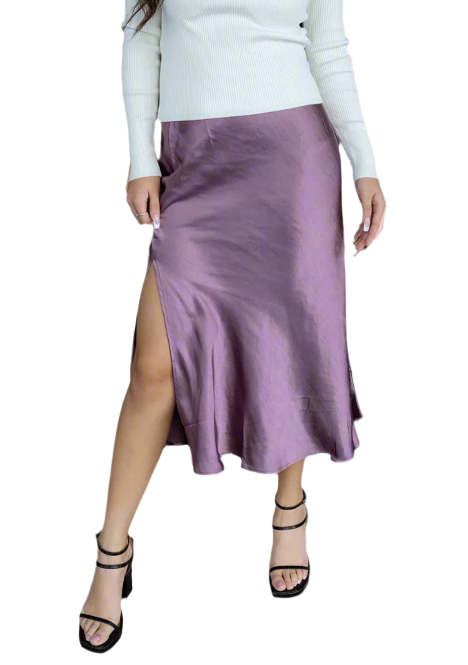 Woman wearing a white long-sleeve top and purple satin skirt on a white background