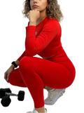 Woman in a red outfit sitting on a white background with a dumbbell beside her.