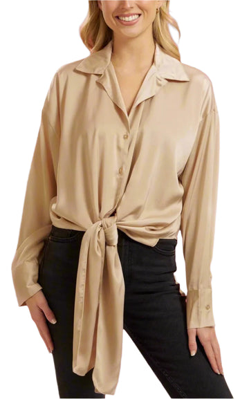 A female model wearing a beige button-down tie front top with a V-neckline and a tie at the waist, paired with black pants.