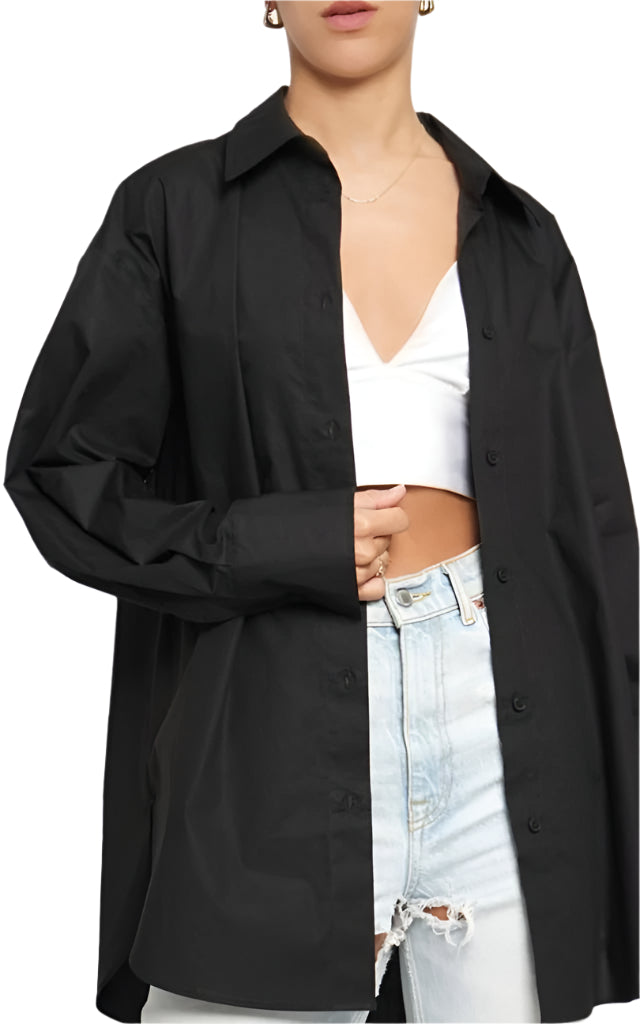 A woman wearing an oversized black button down shirt with a collar and long sleeves, paired with a white cropped top and blue ripped jeans.