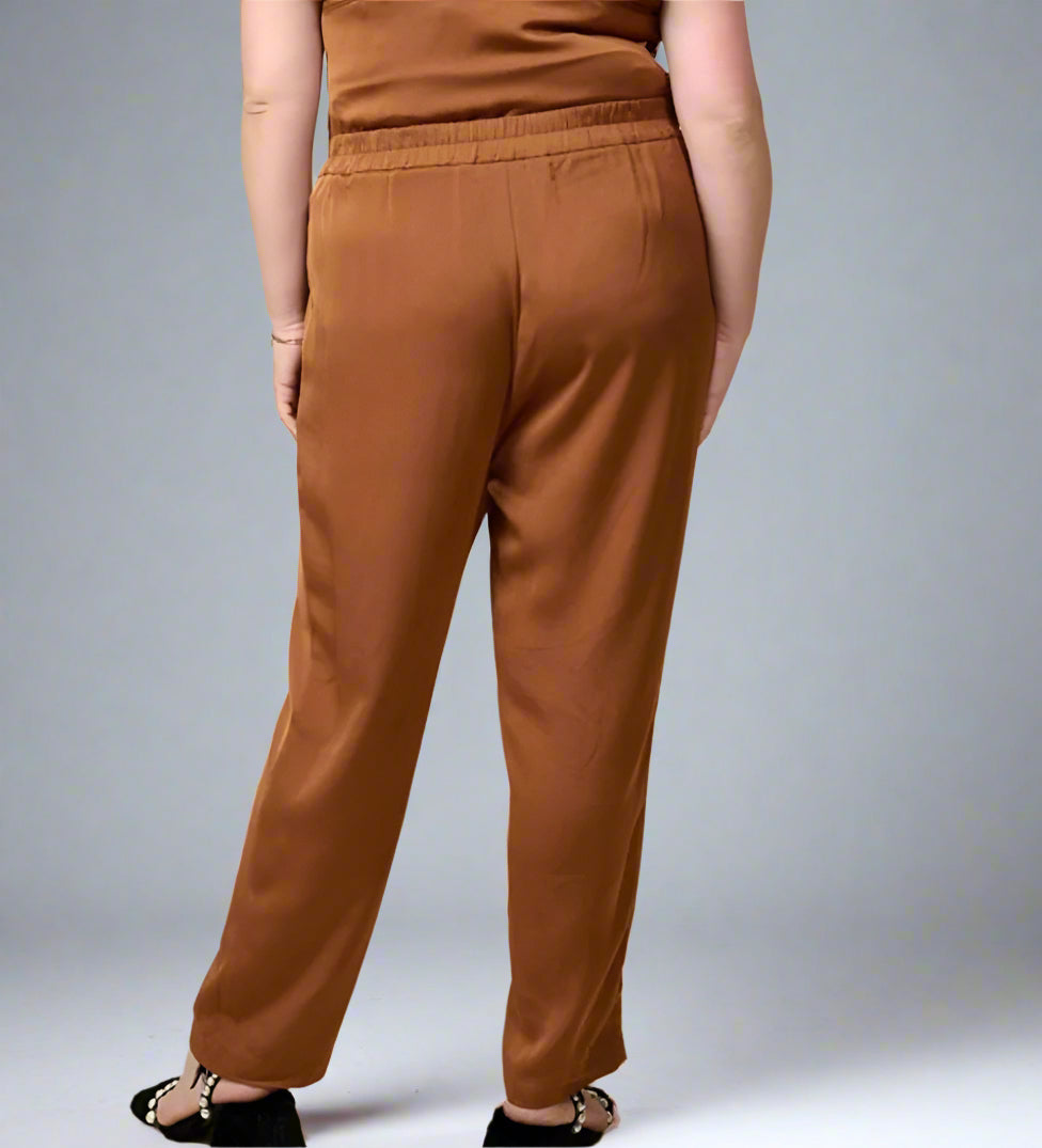 A person standing wearing brown trouser pants with elastic and pockets.