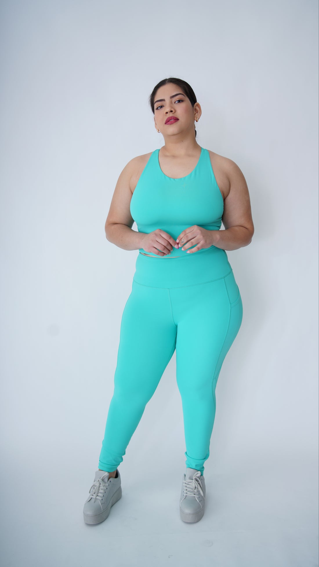 Woman wearing a turquoise athletic outfit on a white background