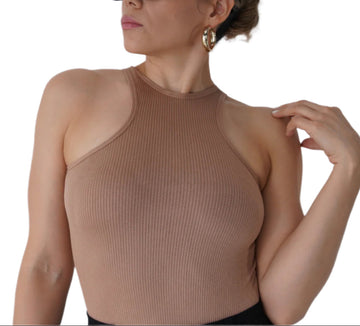 Woman wearing a beige ribbed top and sunglasses against a plain background