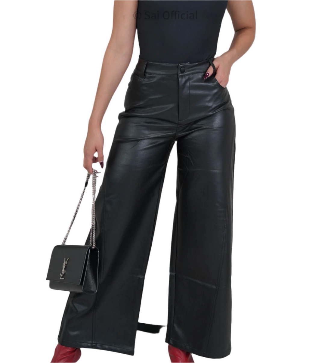 A model wearing mid-rise, wide-leg faux leather pants with a top holding a black purse and red shoes.