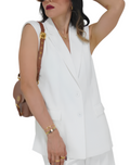 Woman wearing a white sleeveless top and shorts with sunglasses on a white background