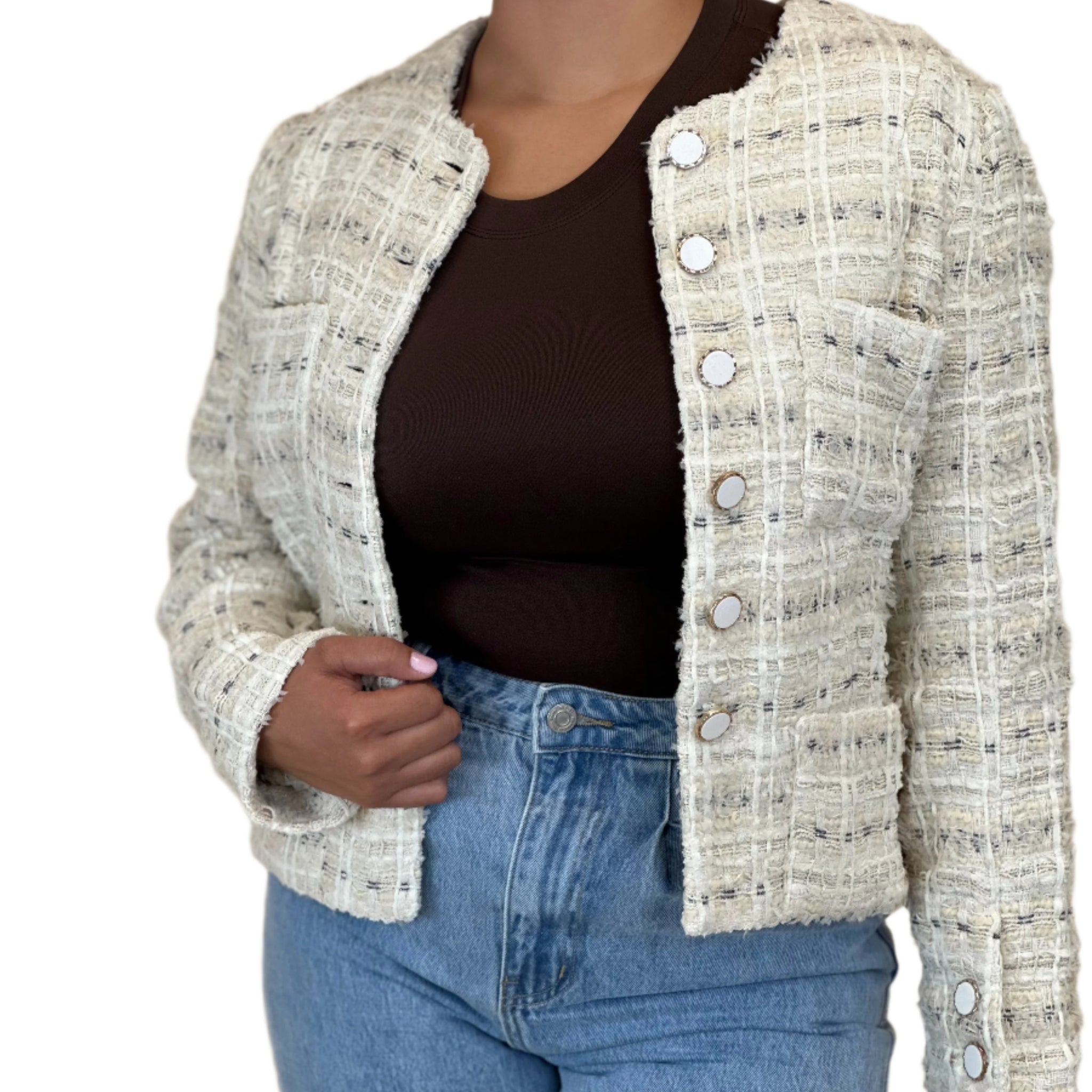 Person wearing a textured beige jacket over a dark top and blue jeans on a beige background