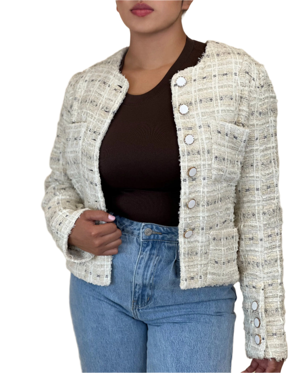 Person wearing a textured beige jacket over a dark top and blue jeans on a beige background