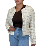 Person wearing a textured beige jacket over a dark top and blue jeans on a beige background
