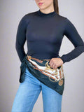 Person wearing a navy blue long-sleeve top with a decorative hip scarf and jeans on a beige background
