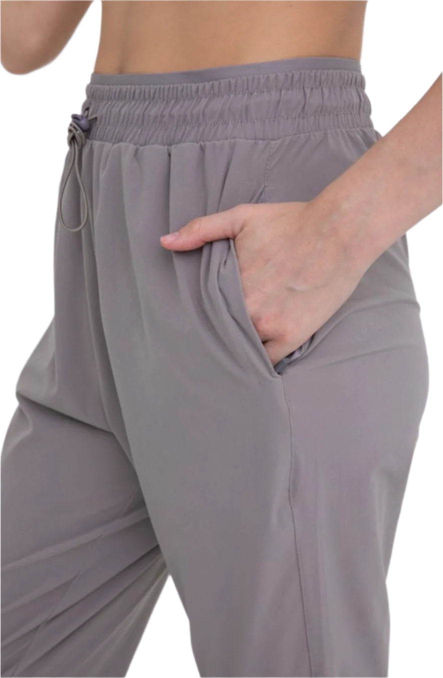 A person wearing gray tapered joggers with adjustable drawstrings at the waist.