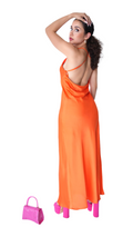 Woman in an orange dress with a pink handbag on a white background