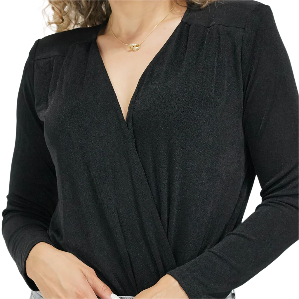 A woman wearing a long sleeve black knit shimmer bodysuit with a V-neckline, paired with blue jeans.