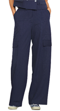 A model wearing navy blue wide leg pants with a striped pattern, featuring multiple pockets.