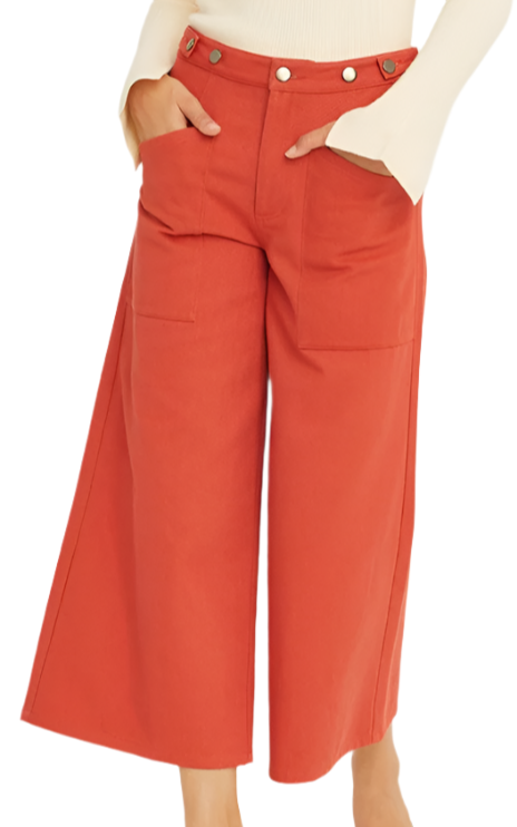 Person wearing red wide-leg pants and a beige top on a white background
