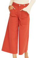 Person wearing red wide-leg pants and a beige top on a white background