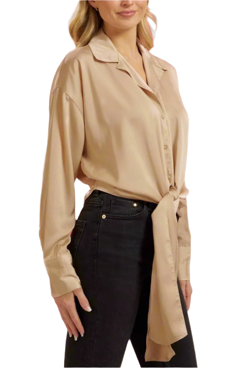 Woman wearing a beige blouse and black pants against a pink background