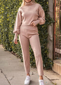 Person wearing a pink outfit with a sweater and pants on a gray background