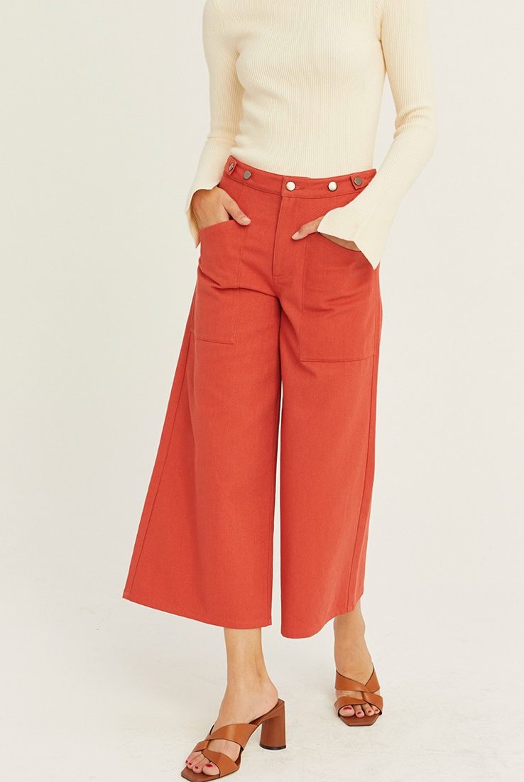 Person wearing red wide-leg pants and a beige top on a white background