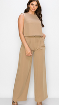 A female model wearing a beige square top with shoulder padding and wide-leg pants set.