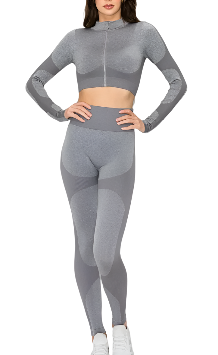 A model wearing a grey seamless 3-piece active set which includes a sports bra top with thumb hole sleeves, a jacket, and leggings.