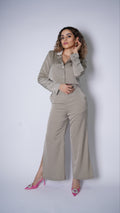 A model wearing a dark brown satin cropped blazer and pants, standing against a white background.